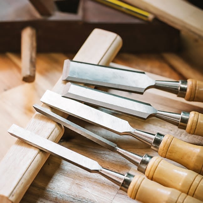 A set of sharp wood chisels laid out on a workbench, ready for detailed joinery
