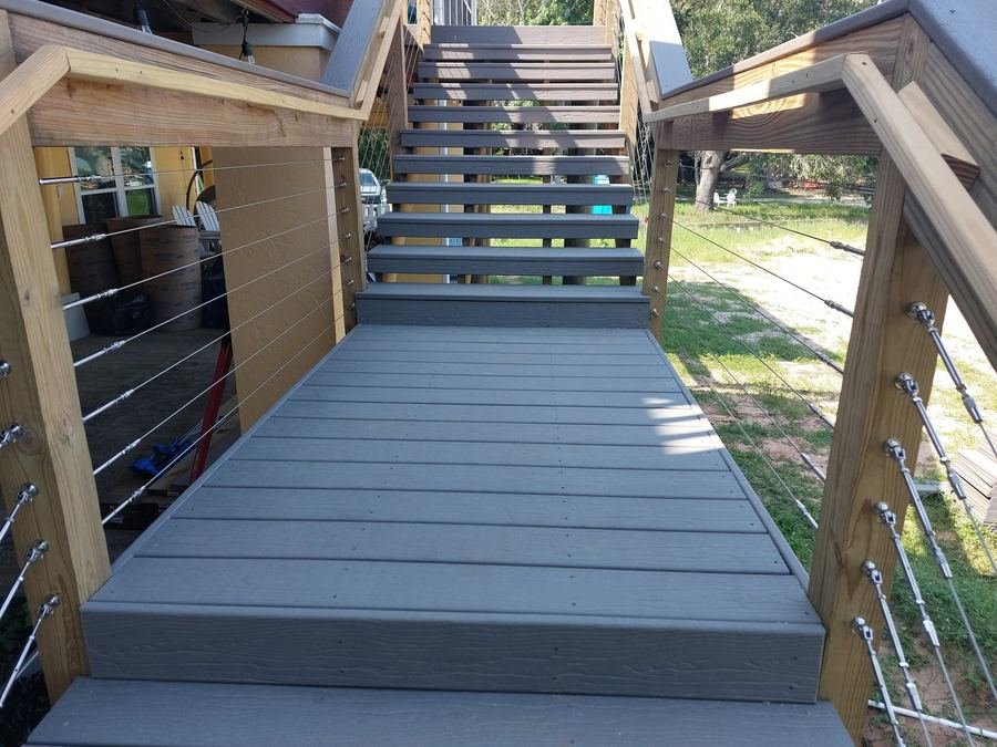 Elevated deck landing with cable railing connecting to an upper staircase