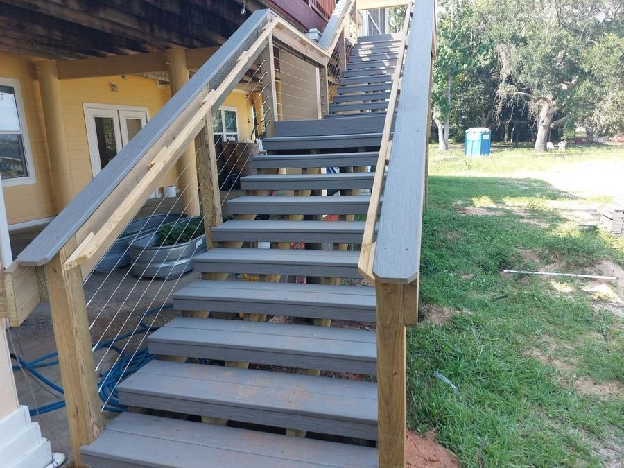 Custom exterior deck staircase with cable railing leading up to a second-story deck