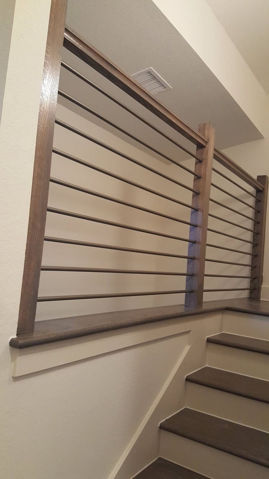 Close-up detail of a wood-framed rod railing system along a stairwell