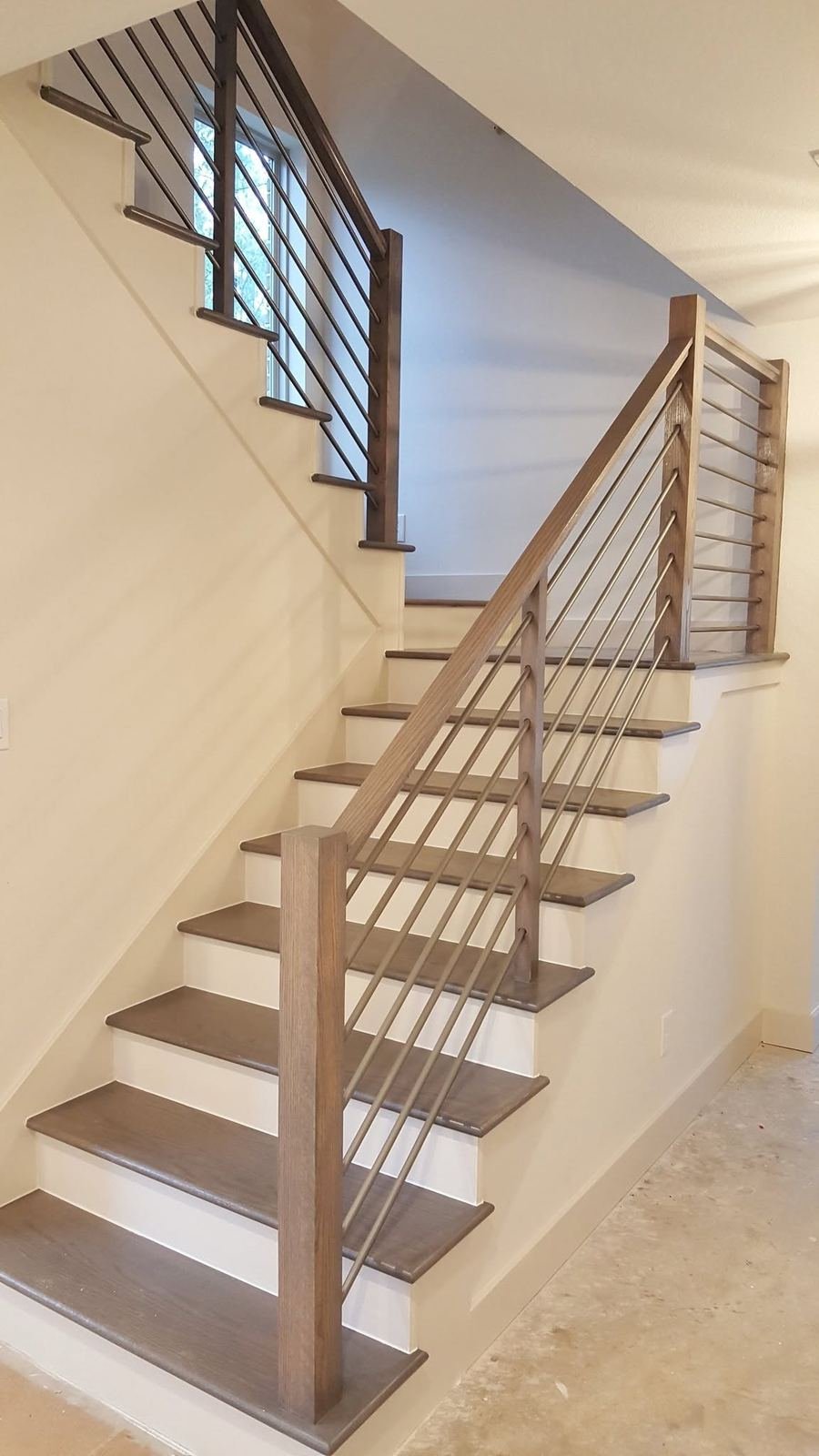 Staircase with wood posts and thin metal rod railings viewed from below